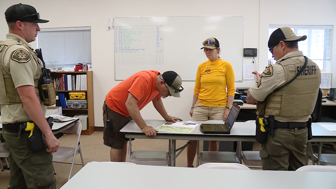 Sgt. Brad Hines (left), John Marshall (center left) and Melissa Nerone (center right) map out a search and rescue call. (KSL TV)