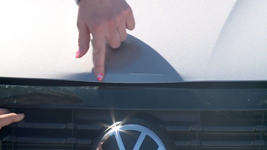 Lynzee Delapaz points to the damage on her car caused by the collision inside the car wash. (Alston Crosby, KSL TV)