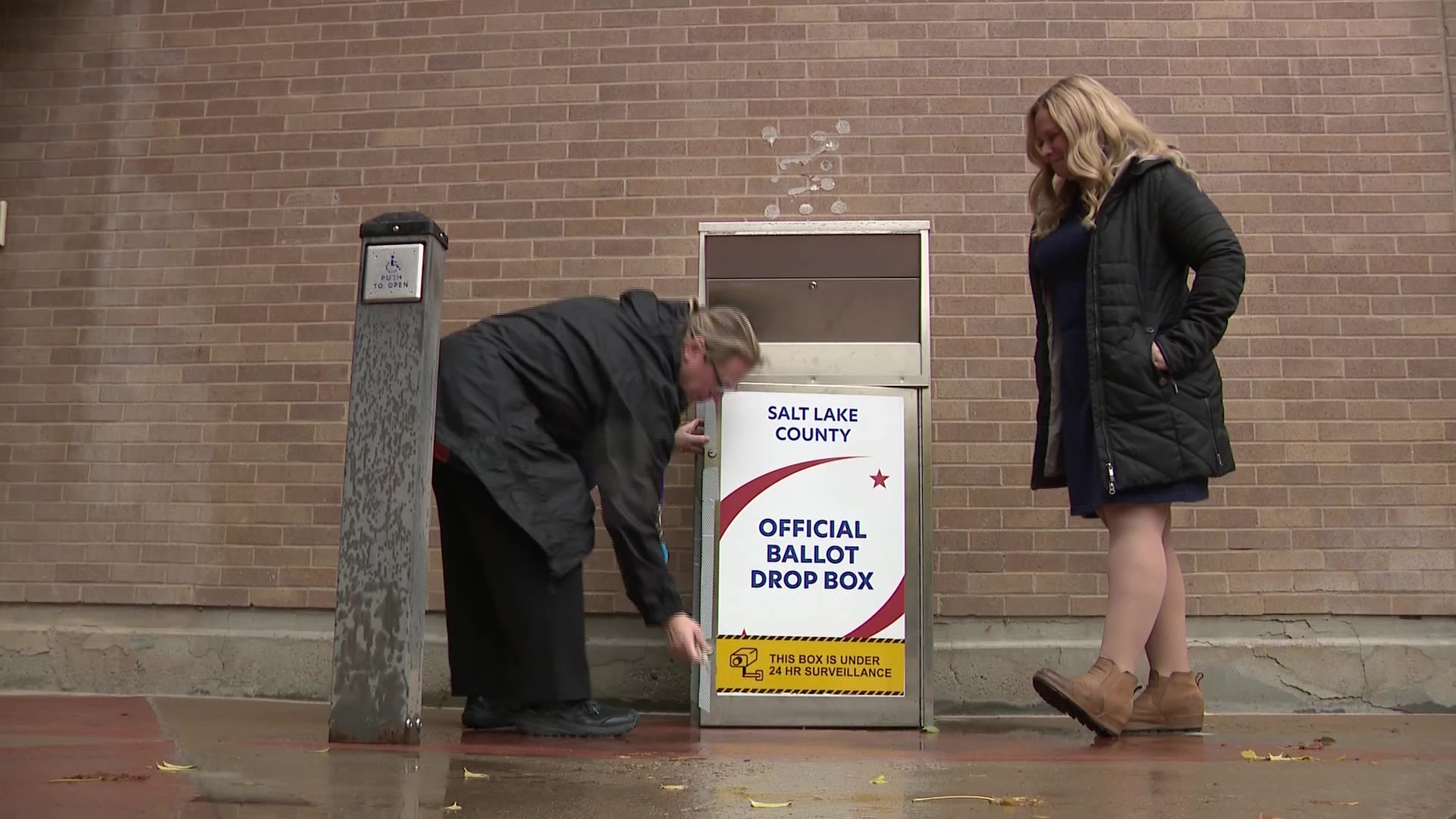 Lannie Chapman and a Salt Lake County election worker opening up a drop box to showcase the safeguards in place on Oct. 29, 2024. (KSL TV)