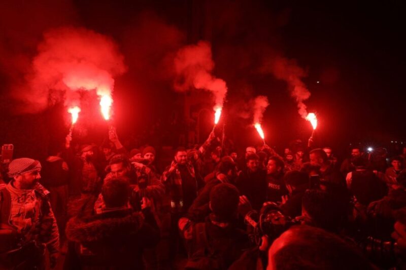 Syrian rebel fighters and locals celebrate in the central city of Homs early on December 8, 2024, after entering Syria's third city overnight. (Abdulaziz Ketaz/AFP/Getty Images)