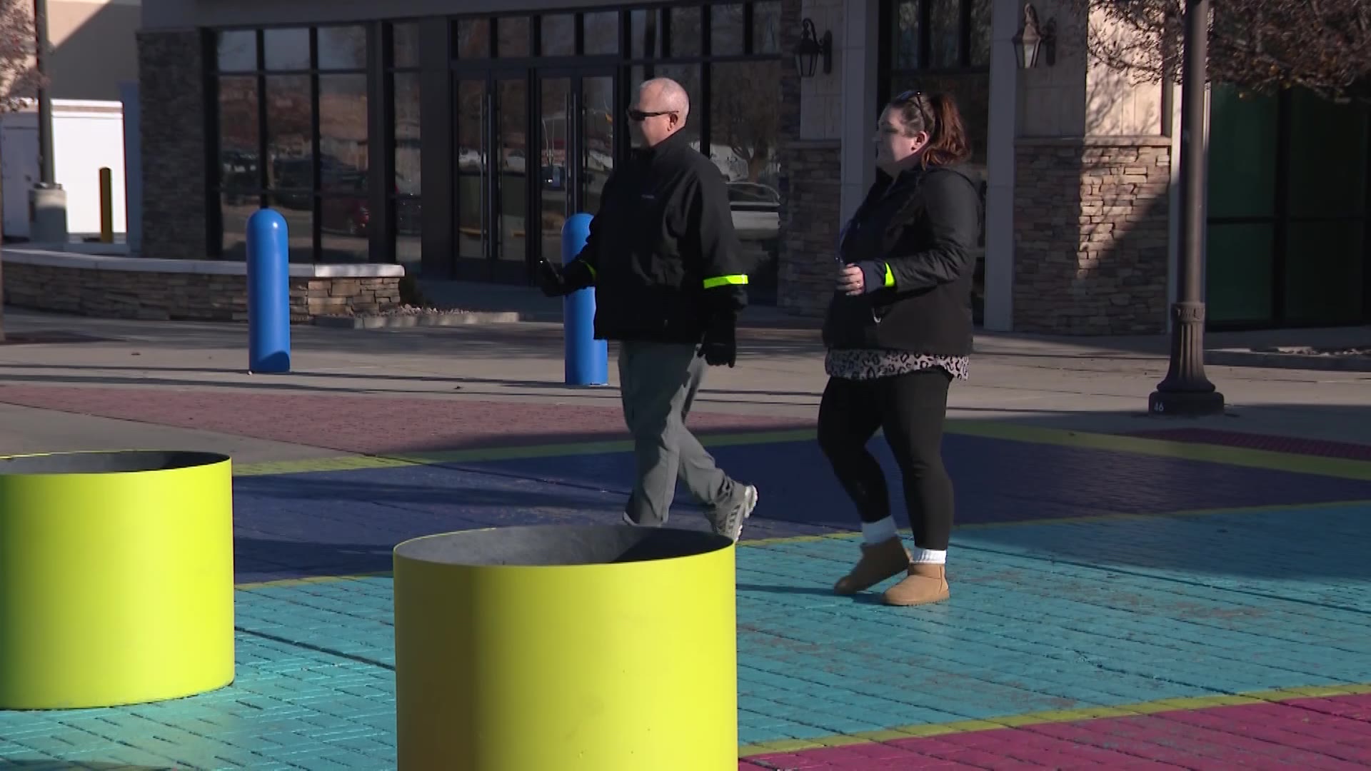 Two demonstrators walking across a crosswalk with reflective wristbands, showing how this could save lives. (Mark Less, KSL TV)