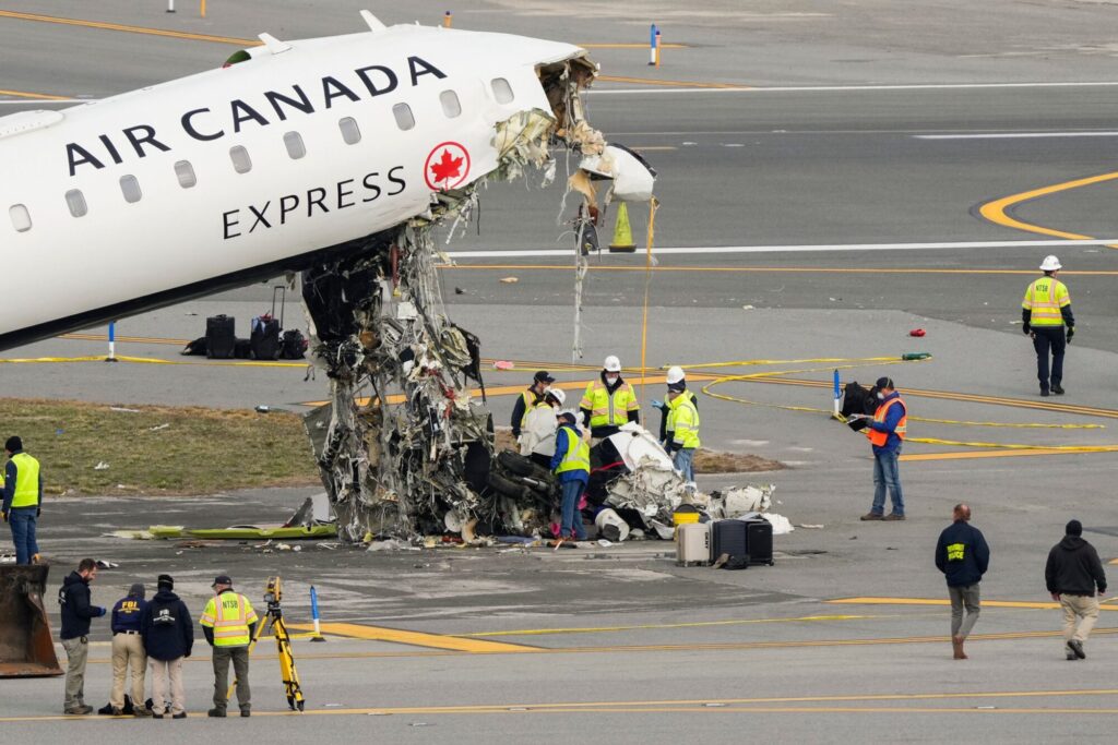 Officials inspect the wreckage of an Air Canada Express regional jet on Wednesday at LaGuardia Airport in New York. (Yuki Iwamura, AP via CNN Newsource)