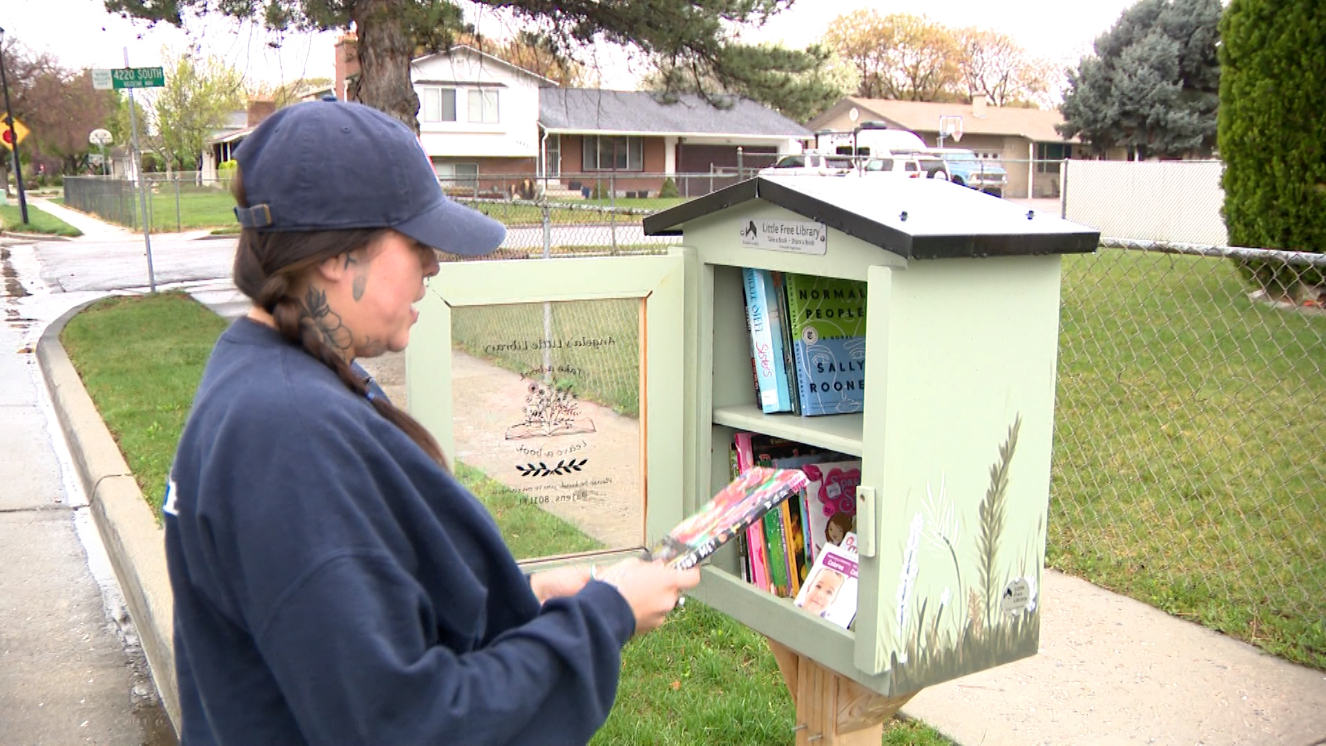 Angela Jensen stands near her Little Free Library in West Valley City on Wednesday, April 1, 2026. (Nathaniel Gillis, KSL)